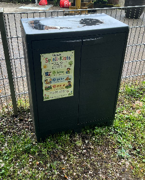 Die neu aufgestellte Spieli-Kiste am Spielplatz am Finkenweg in Sirnau, gefüllt mit buntem Sandspielzeug und Sportgeräten.